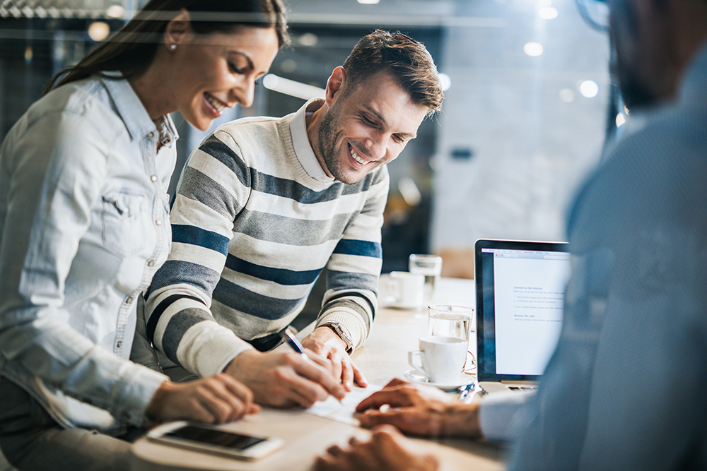 Happy couple signing a contract on a business meeting with their insurance agent.